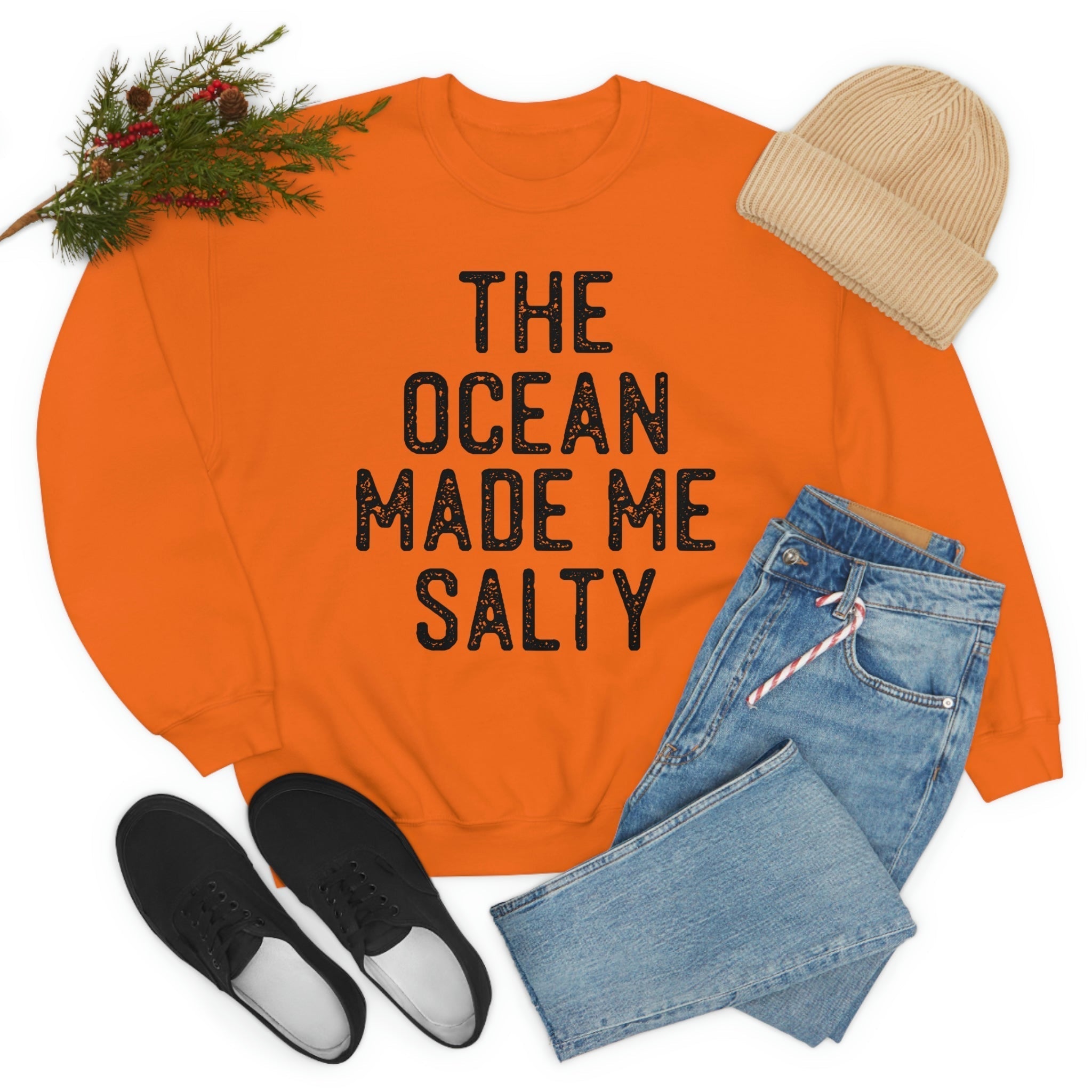 The Ocean Made Me Salty sweatshirt in vibrant orange, styled with jeans and a cozy beanie.