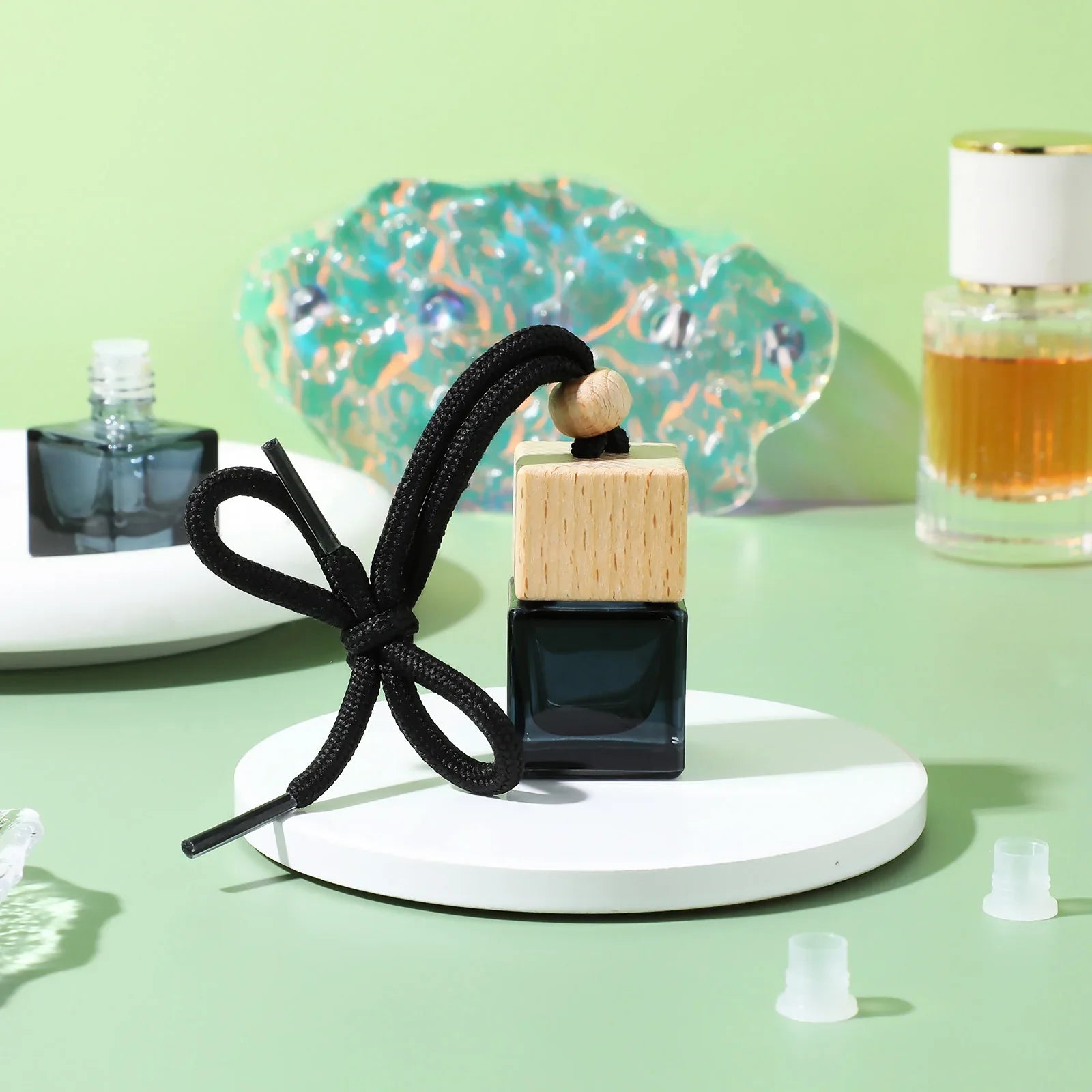 Hanging car perfume diffuser with wood cap displayed on a white platform, enhancing car interior elegance.