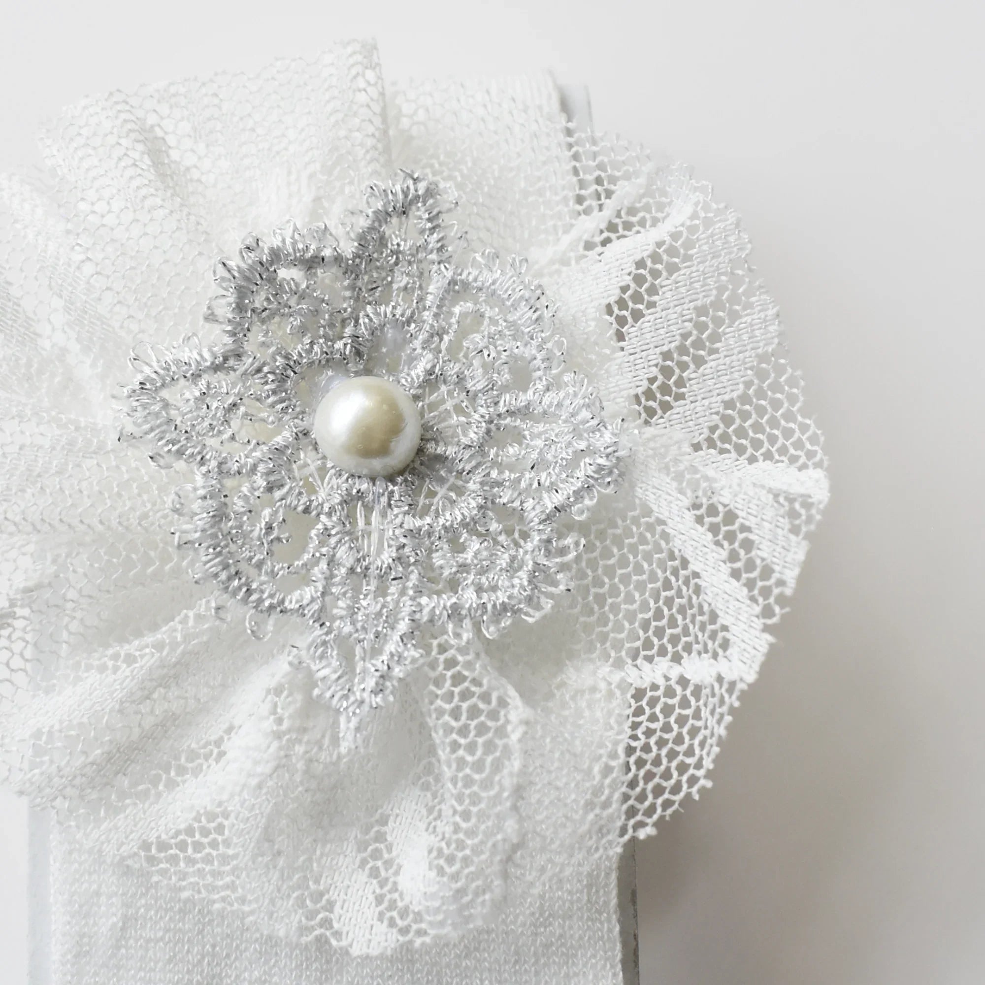 Baby Bliss Baby Shoes Set headband with elegant silver flower and pearl detail on soft white fabric.