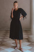 Freya Smocked Linen Midi Dress worn by a model, featuring tie up puff sleeves and a elegant black design.