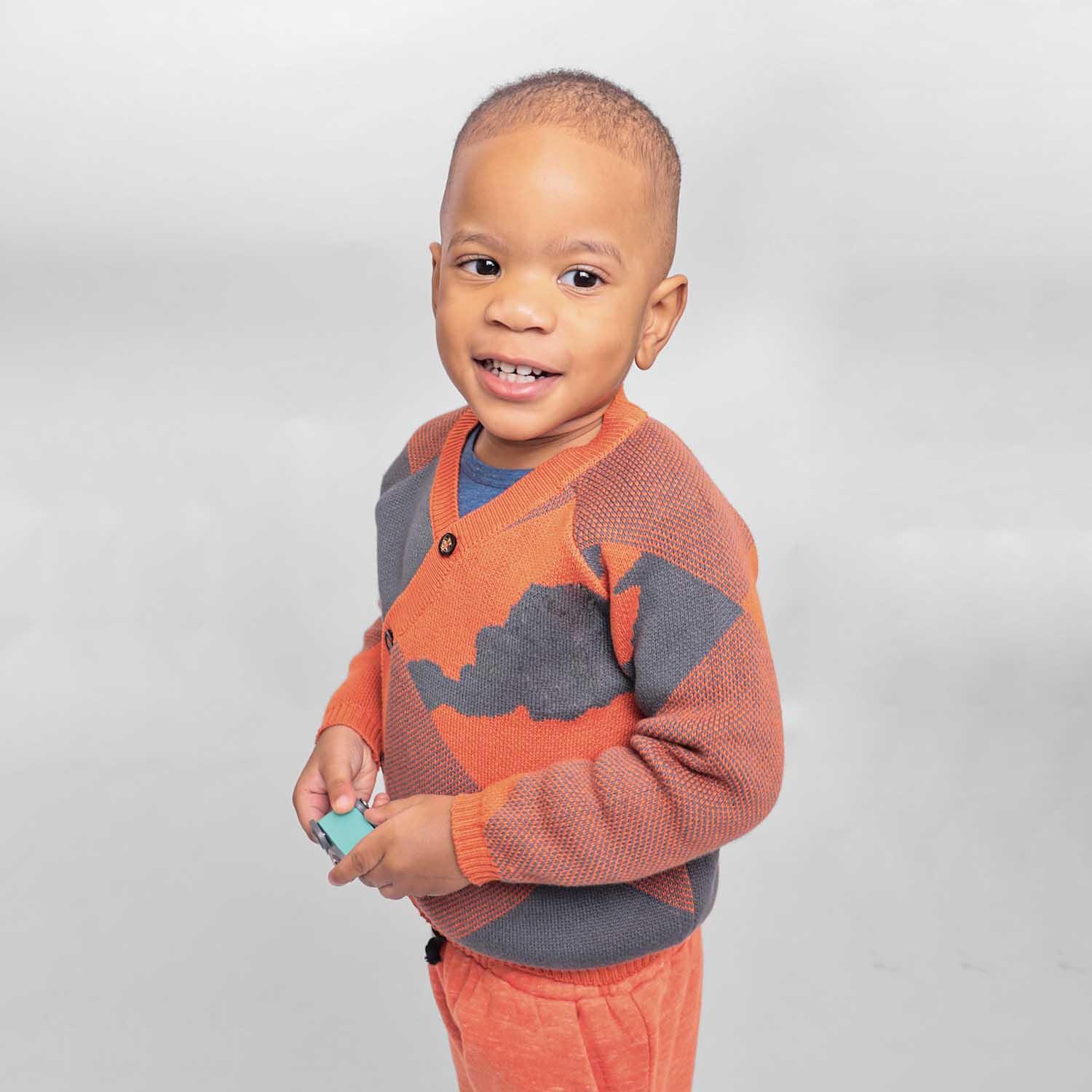 Baby Cardigan in Blue and Orange worn by a smiling toddler, showcasing cozy style and vibrant colors.