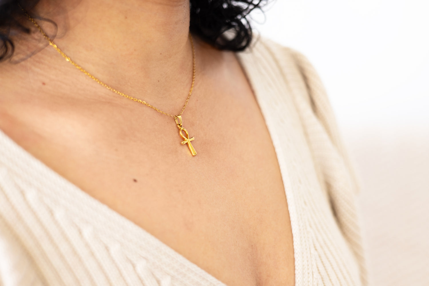 Close-up of a gold ankh necklace worn with style, accentuating a chic and modern look.